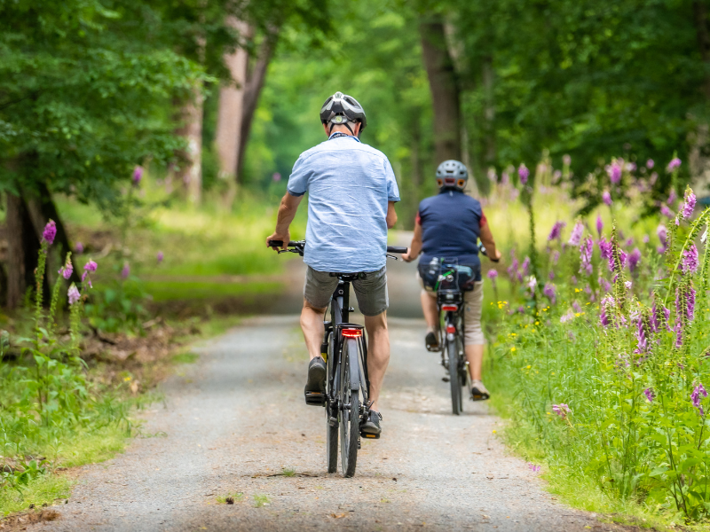 A photo of a man and woman cycling through a park.